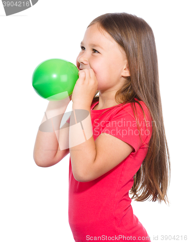 Image of Little girl is inflating green balloon