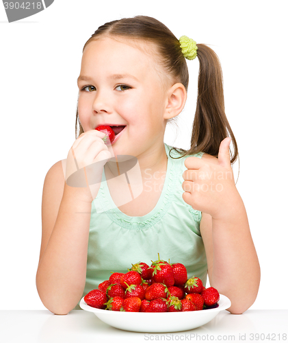 Image of Happy little girl is eating strawberries