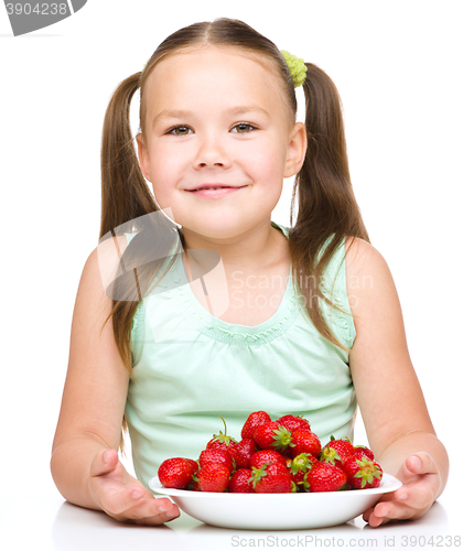 Image of Cheerful little girl is eating strawberries