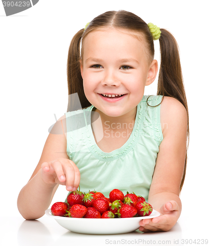 Image of Cheerful little girl is eating strawberries