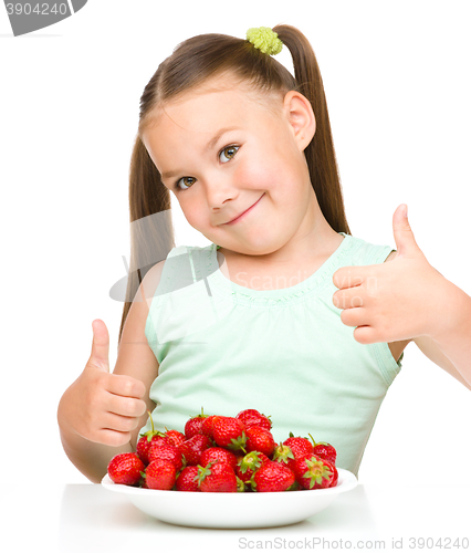 Image of Happy little girl is eating strawberries