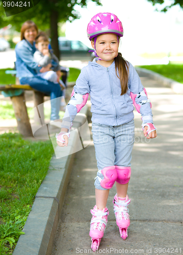 Image of Happy little girl is skating on rollers