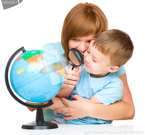 Image of Mother is looking at globe with her son