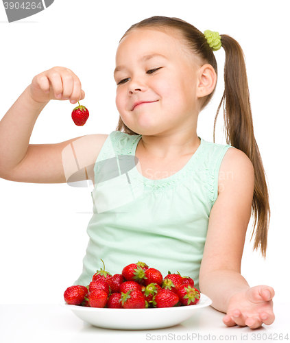 Image of Cheerful little girl is eating strawberries