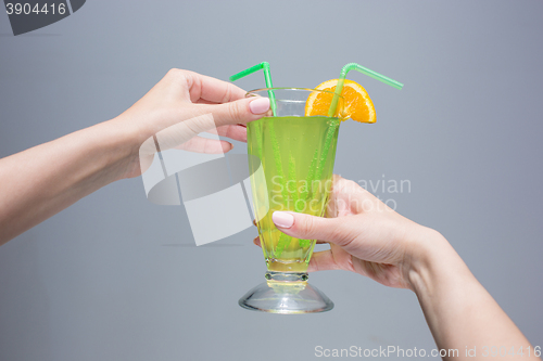 Image of The female hands with cocktail on gray background