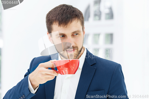 Image of Businessman having coffee break, he is holding a cup 