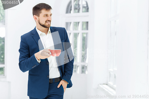 Image of Businessman having coffee break, he is holding a cup 