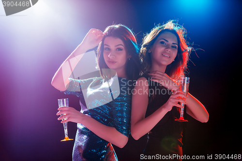 Image of Two beautiful girls dancing at the party drinking champagne