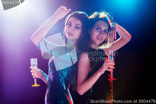Image of Two beautiful girls dancing at the party drinking champagne