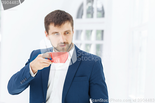 Image of Businessman having coffee break, he is holding a cup 