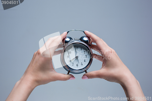 Image of The female hands and old style alarm clock 