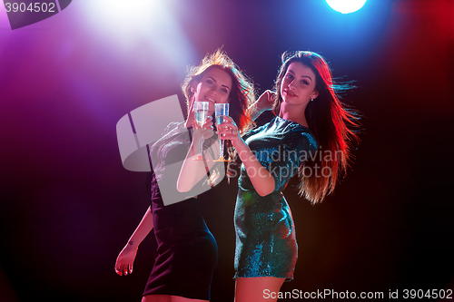 Image of Two beautiful girls dancing at the party drinking champagne