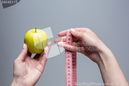Image of Green apple in female hands on gray background. Weight loss, diet