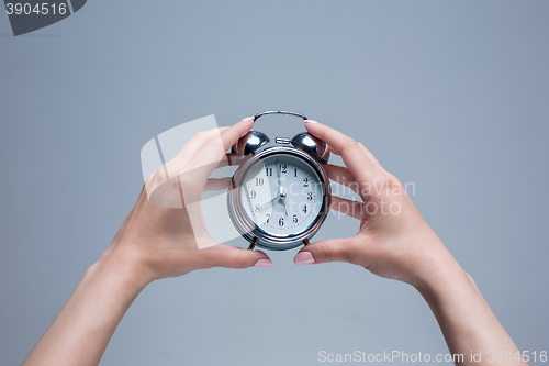 Image of The female hands and old style alarm clock 