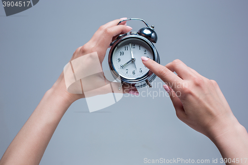 Image of The female hands and old style alarm clock 