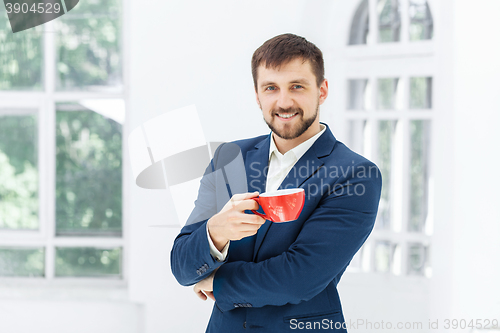 Image of Businessman having coffee break, he is holding a cup 