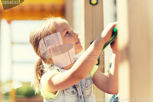 Image of happy little girl climbing on children playground