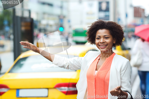 Image of happy african woman catching taxi