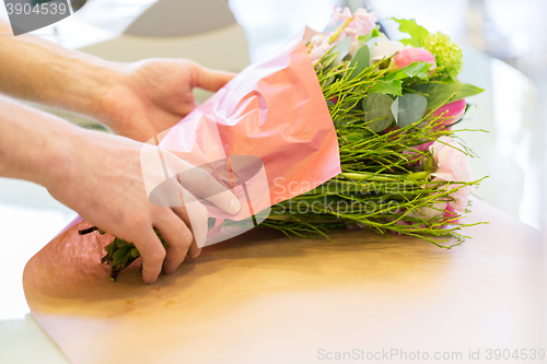 Image of florist wrapping flowers in paper at flower shop