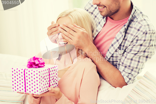 Image of happy man giving woman gift box at home