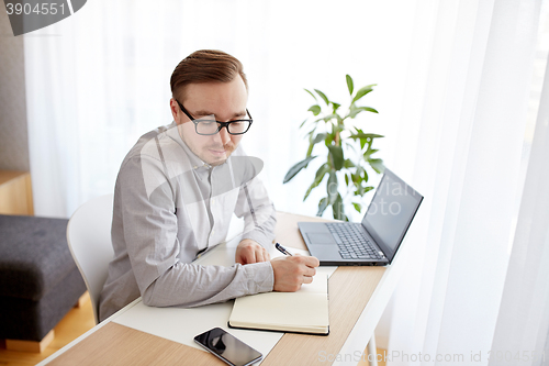Image of creative man or businessman writing to notebook