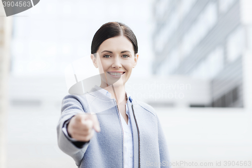 Image of young smiling businesswoman over office building