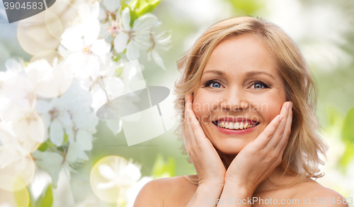 Image of smiling woman with bare shoulders touching face