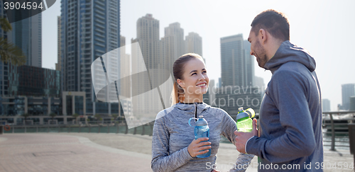 Image of smiling couple with bottles of water in city