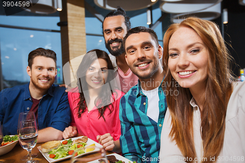 Image of friends taking selfie by smartphone at restaurant