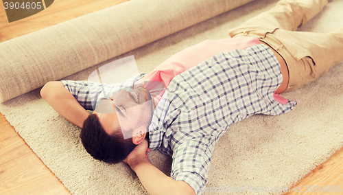 Image of happy man lying carpet or rug at home