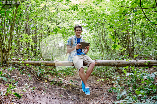 Image of happy man with backpack and tablet pc in woods