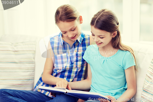 Image of two happy girls reading book at home