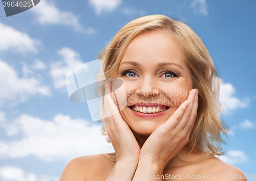 Image of smiling woman with bare shoulders touching face