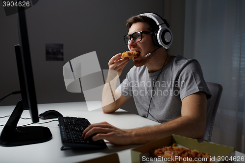 Image of man in headset playing computer video game at home