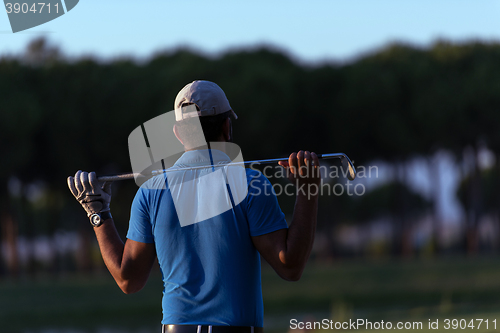 Image of golfer from back at course looking to hole in distance