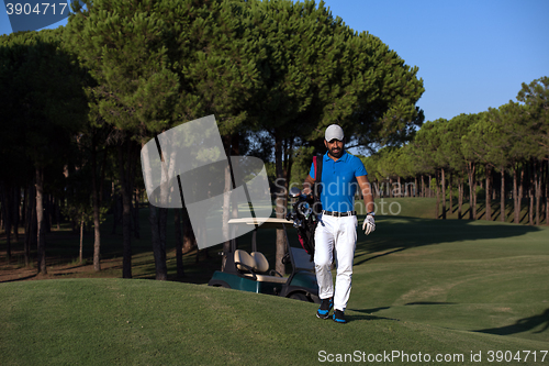 Image of golfer  walking and carrying golf  bag