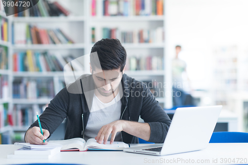 Image of student in school library using laptop for research