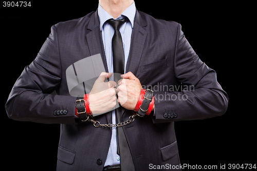 Image of man in a business suit with leather bound. handcuffs. sex Toys