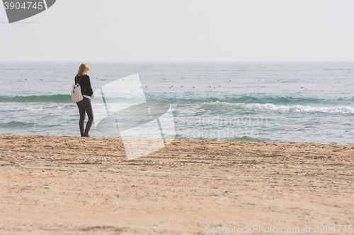 Image of A young girl stands on the seashore and looks at the sea