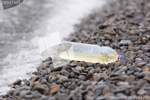 Image of Plastic bottle lying on the pebbly seashore