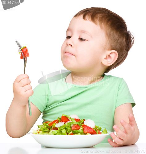 Image of Cute little boy is eating vegetable salad