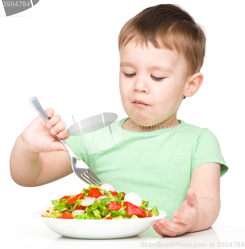 Image of Cute little boy is eating vegetable salad