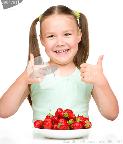 Image of Happy little girl is eating strawberries