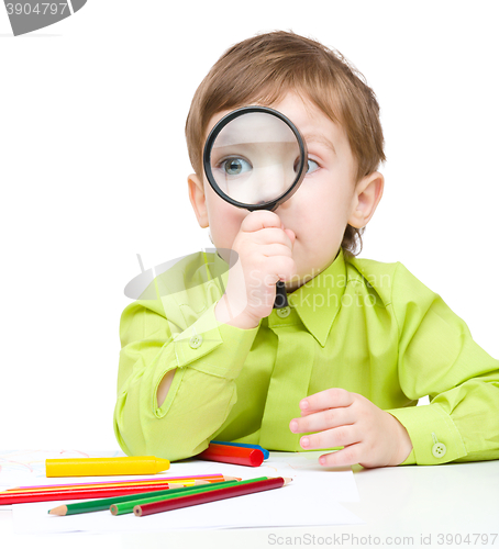 Image of Cute little boy is playing with magnifier