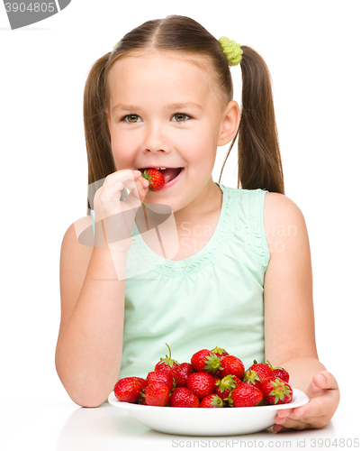 Image of Happy little girl is eating strawberries