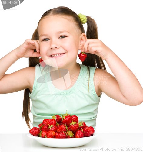 Image of Cheerful little girl is eating strawberries