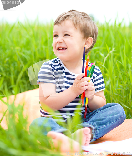 Image of Little boy is playing with pencils