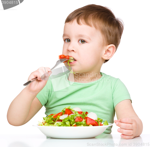 Image of Cute little boy is eating vegetable salad