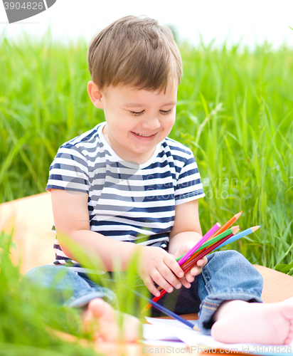 Image of Little boy is playing with pencils