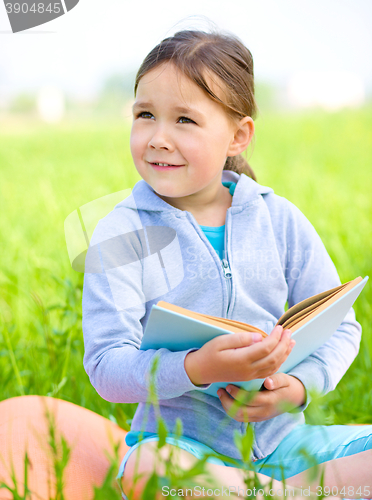 Image of Little girl is reading a book outdoors